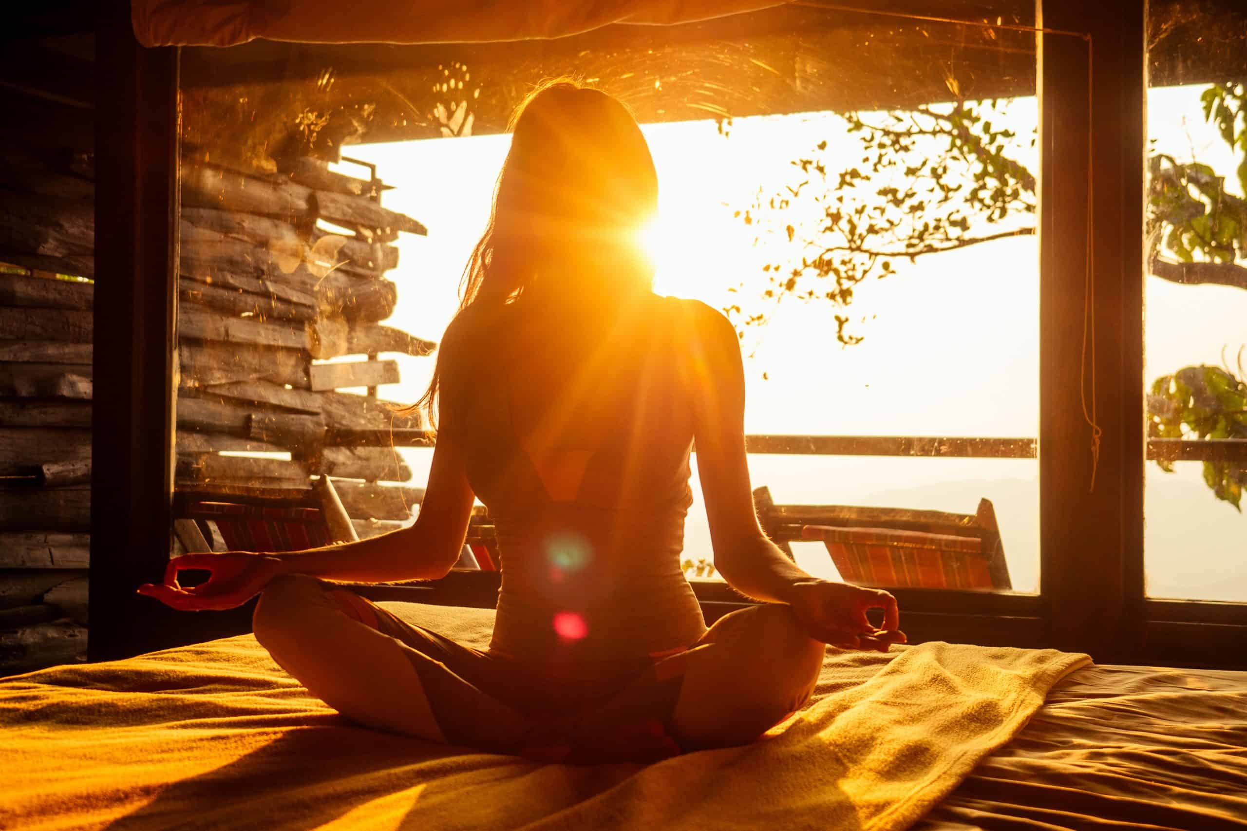 Frau im Sonnenaufgang, Meditationssitz mit Chakrenanzeige